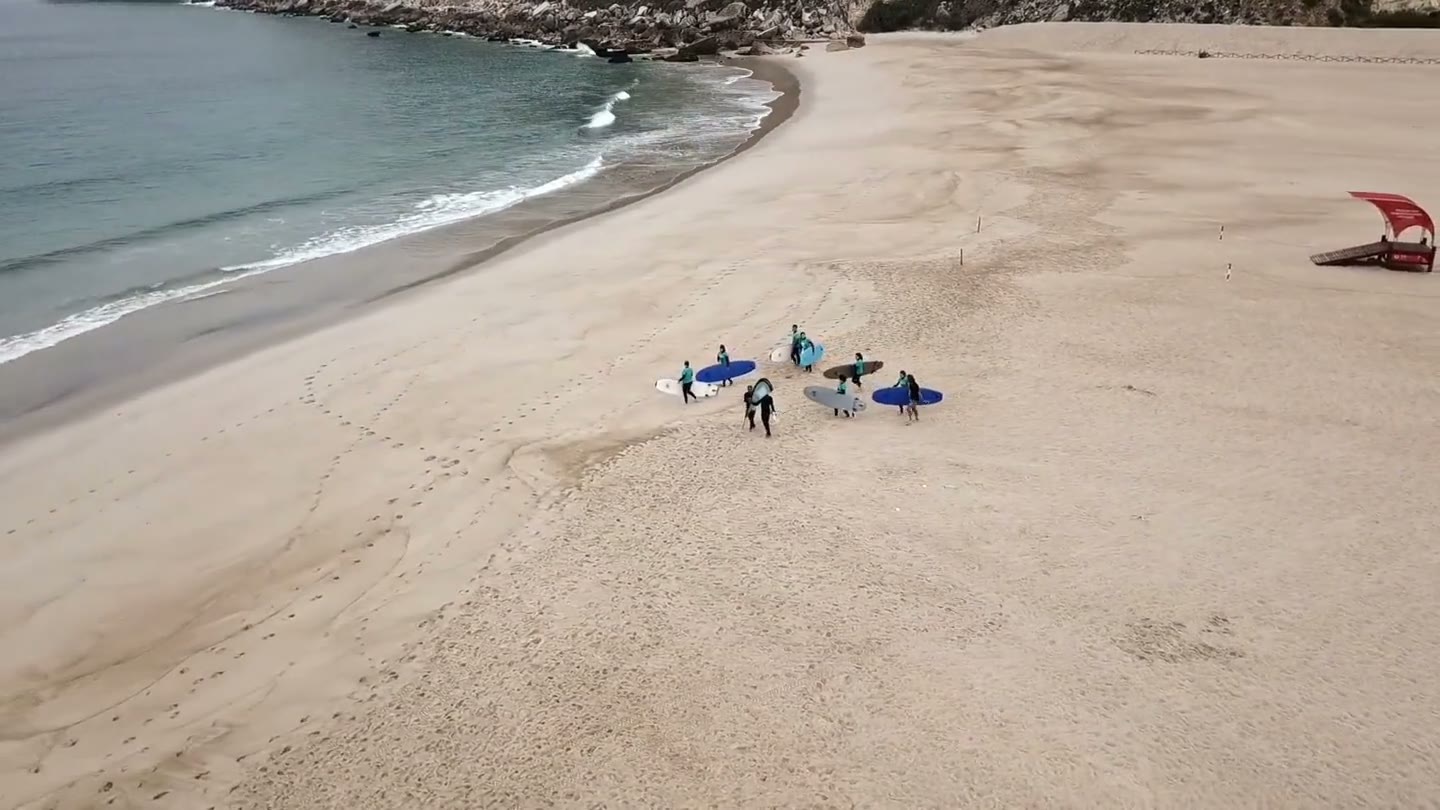 Aerial view of Nazare Surf School students carrying boards across the beach